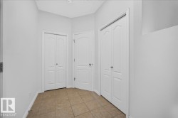 Hallway featuring neutral-toned ceramic tile flooring, light gray wall paint, and multiple white panel doors - 