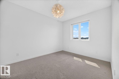 Bright room featuring a single window, a contemporary ceiling light fixture, neutral carpet flooring, white walls, and white trim - 8508 218 Street, Edmonton, AB 