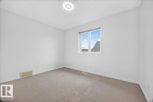 Neutral-toned carpeting paired with white walls, baseboards, and trim - 8508 218 Street, Edmonton, AB 