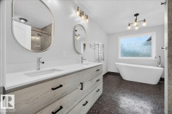 Bathroom featuring a freestanding tub, dual vanity with undermount sinks, and a walk-in shower with glass enclosure - 