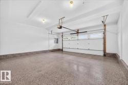 Spacious two-car garage featuring a speckled epoxy floor, white paneled garage door with upper windows, and an automatic garage door opener - 