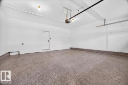 Spacious garage featuring a durable epoxy floor coating, crisp white walls, and a convenient service door - 