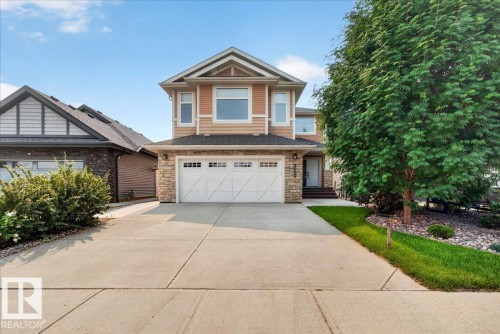 Two-story residence featuring a two-car garage, stone and siding exterior, concrete driveway, and mature landscaping - 8508 218 Street, Edmonton, AB 