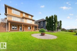 Expansive green lawn featuring a circular gravel fire pit area - 