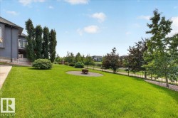 Expansive green lawn with a circular gravel fire pit area - 