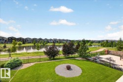 Expansive backyard featuring a green lawn, established landscaping, and a fire pit area - 