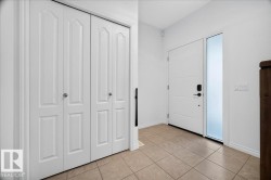 Entryway featuring a white paneled front door with a frosted sidelight, tile flooring, and a bifold closet with white panel doors - 