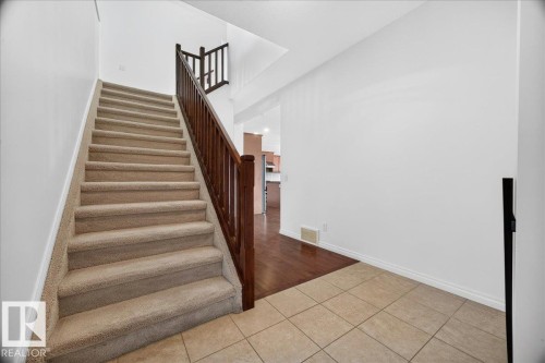Staircase with carpeted treads and risers, featuring a dark wood-finish railing and balusters - 8508 218 Street, Edmonton, AB 
