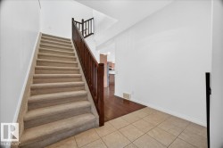 Staircase with carpeted treads and risers, featuring a dark wood-finish railing and balusters - 