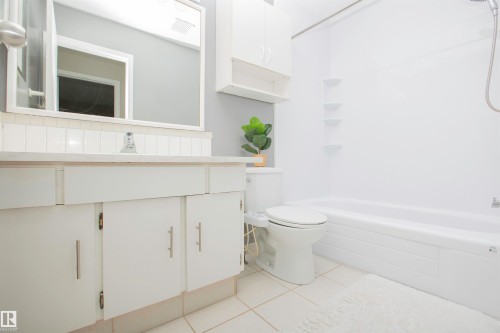Bathroom featuring a white vanity with panel cabinetry, a white countertop, and a rectangular mirror - 3531 46 Street, Edmonton, AB 