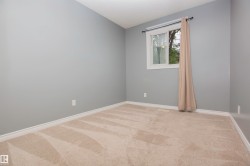 Carpeted interior space featuring light grey walls, white baseboards, and a white framed window - 