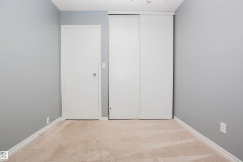 Room featuring light grey walls, light-colored carpeting, white baseboards, and a white interior door - 3531 46 Street, Edmonton, AB 