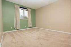 Carpeted room featuring a window with natural light, neutral wall colors, and white baseboards - 