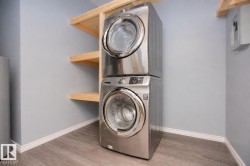 Stackable laundry appliances with front-loading design, complemented by wood shelving and wood-finish flooring - 