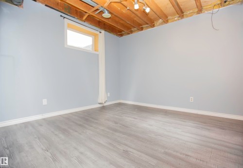 Spacious room with light gray walls, wood-finish flooring, and white baseboards - 3531 46 Street, Edmonton, AB 