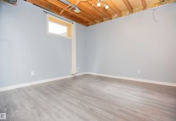 Spacious room with light gray walls, wood-finish flooring, and white baseboards - 