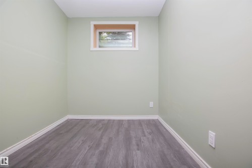 Room featuring light green walls, white trim, and wood-finish flooring - 3531 46 Street, Edmonton, AB 