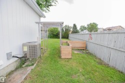 Private backyard featuring a wooden privacy fence, green lawn, and raised garden beds - 