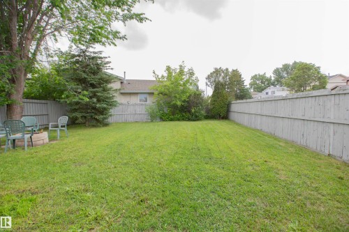 Expansive backyard featuring a manicured lawn, established trees, and a full perimeter wood fence - 3531 46 Street, Edmonton, AB 