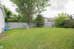 Expansive green lawn with mature trees and a privacy fence - 