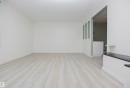 Spacious interior room featuring light wood-finish flooring, white walls, and a partial wall with decorative cutouts - 3531 46 Street, Edmonton, AB 