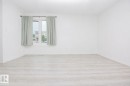 Bright room featuring a large window, light wood-finish flooring, white walls, and white baseboards - 3531 46 Street, Edmonton, AB 