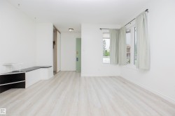 Bright living area with wood-finish flooring, white walls, and multiple windows - 