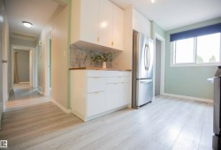 Kitchenette featuring contemporary white cabinetry with gold-tone hardware, a wood-finish countertop, and a decorative tile backsplash - 
