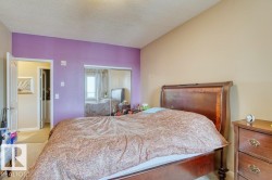 Bedroom featuring a purple accent wall, neutral tone walls, and mirrored sliding closet doors - 