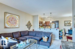 Open-concept living space featuring a kitchen with dark wood-finish cabinetry, a built-in microwave, and a breakfast bar with pendant lighting - 