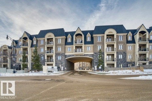 Multi-story residential building featuring a stone and stucco facade, a dark sloped roof, and multiple private balconies - 319 6083 Maynard Way, Edmonton, AB 