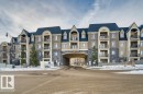 Multi-story residential building featuring a stone and stucco facade, a dark sloped roof, and multiple private balconies - 319 6083 Maynard Way, Edmonton, AB 