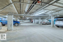 Underground parking facility featuring concrete construction, exposed utility piping, and fluorescent lighting - 