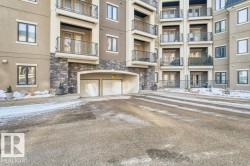 Multi-story building exterior featuring balconies with wrought iron railings and a stone facade foundation - 