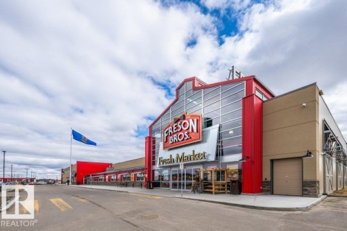 Contemporary commercial building featuring a prominent glass and red facade - 319 6083 Maynard Way, Edmonton, AB 