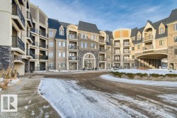 Multi-story building featuring stone veneer accents, stucco siding, a gabled roofline, and individual balconies with black railings - 