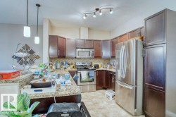Kitchen featuring dark wood-finish cabinetry, stainless steel appliances, granite countertops, and a tile backsplash - 