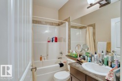 Full bathroom featuring a shower-over-tub combination with tile surround, a built-in vanity with an integrated sink, and a large wall-mounted mirror - 