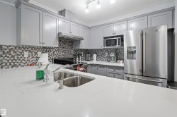 Kitchen featuring white countertops, grey shaker-style cabinetry, and a mosaic tile backsplash - 
