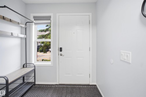 Entryway featuring a white paneled door with smart lock hardware, a large side window, and light gray wall finishes - 92 230 Edwards Drive, Edmonton, AB 