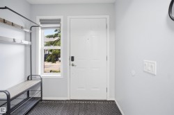 Entryway featuring a white paneled door with smart lock hardware, a large side window, and light gray wall finishes - 