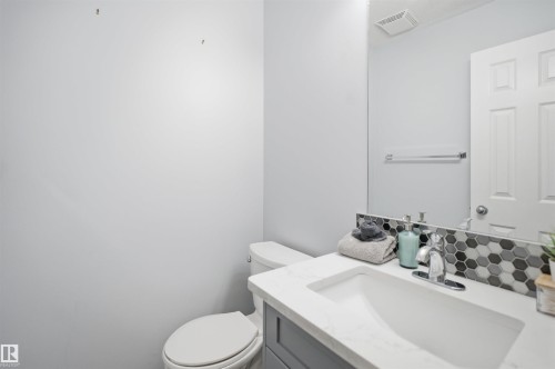 Bathroom vanity featuring a rectangular undermount sink, a countertop with a marble-effect finish, and a hexagonal tile backsplash - 92 230 Edwards Drive, Edmonton, AB 