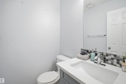 Bathroom vanity featuring a rectangular undermount sink, a countertop with a marble-effect finish, and a hexagonal tile backsplash - 