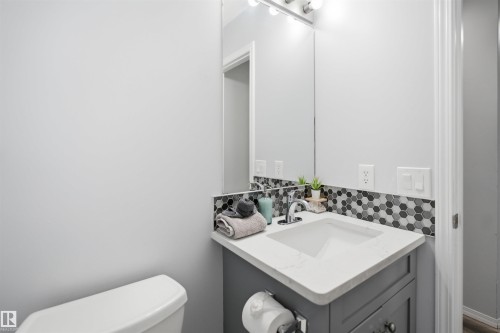 Modern vanity featuring a white countertop with integrated sink, chrome faucet, and gray cabinetry - 92 230 Edwards Drive, Edmonton, AB 