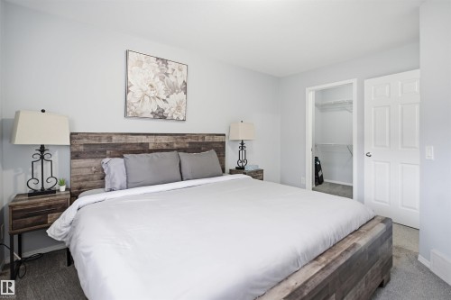 Bedroom featuring wood-finish flooring, light gray wall paint, and a built-in closet with shelving - 92 230 Edwards Drive, Edmonton, AB 