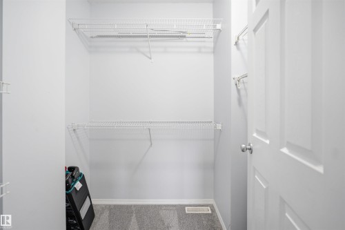 Walk-in closet featuring wire shelving, white painted walls, and gray carpet flooring - 92 230 Edwards Drive, Edmonton, AB 