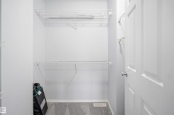 Walk-in closet featuring wire shelving, white painted walls, and gray carpet flooring - 