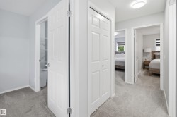 Carpeted hallway featuring white paneled doors, a flush-mount ceiling light, and built-in closet storage - 