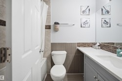 Bathroom featuring a single vanity with a white countertop, under-mount sink, and gray cabinetry - 