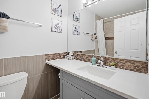 Bathroom vanity featuring an integrated rectangular sink, chrome faucet, and white countertop - 92 230 Edwards Drive, Edmonton, AB 